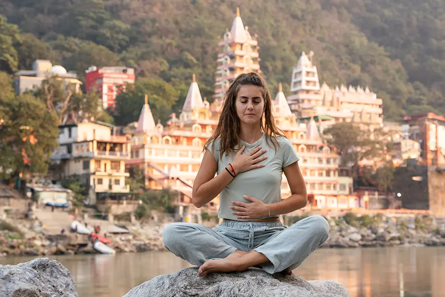 Yoga Teacher Training Courses - Girl meditating close to Ganga